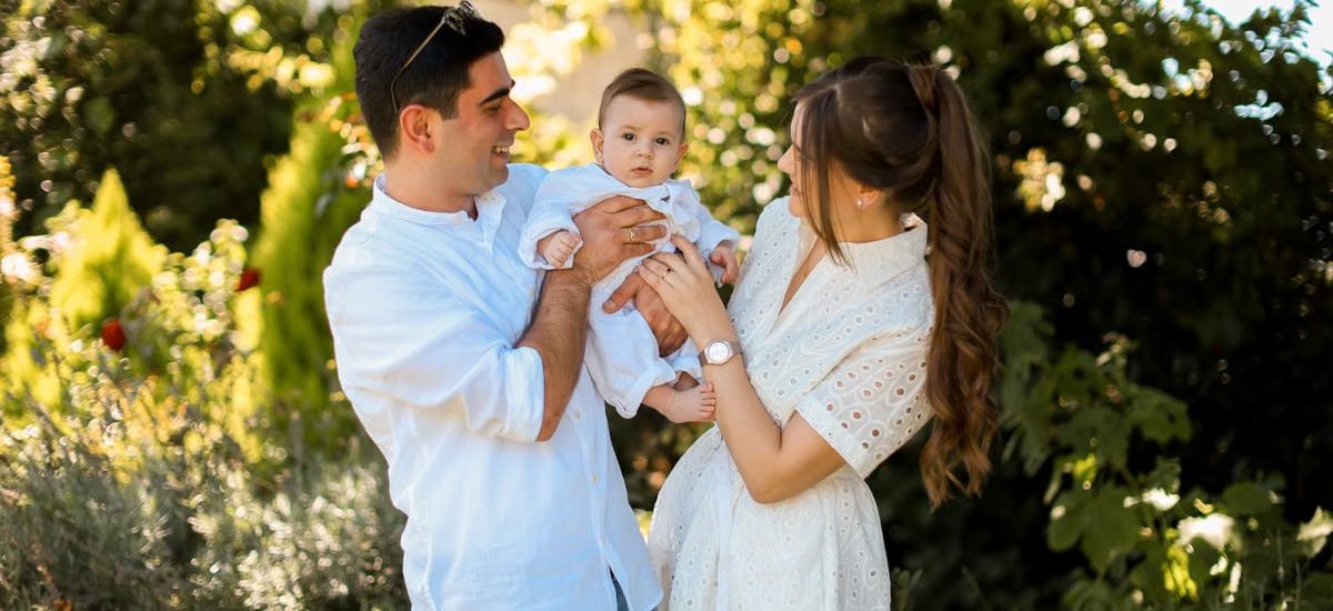 A joyful young family spending quality time together in a sunny outdoor park setting.