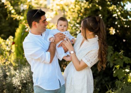 A joyful young family spending quality time together in a sunny outdoor park setting.